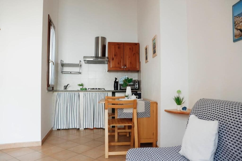 A compact kitchen with a dining area, wooden cabinets, and a striped tablecloth.