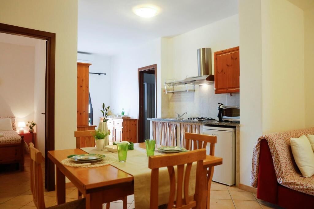 Una cocina compacta con gabinetes de madera, estufa a gas y campana extractora de acero inoxidable.