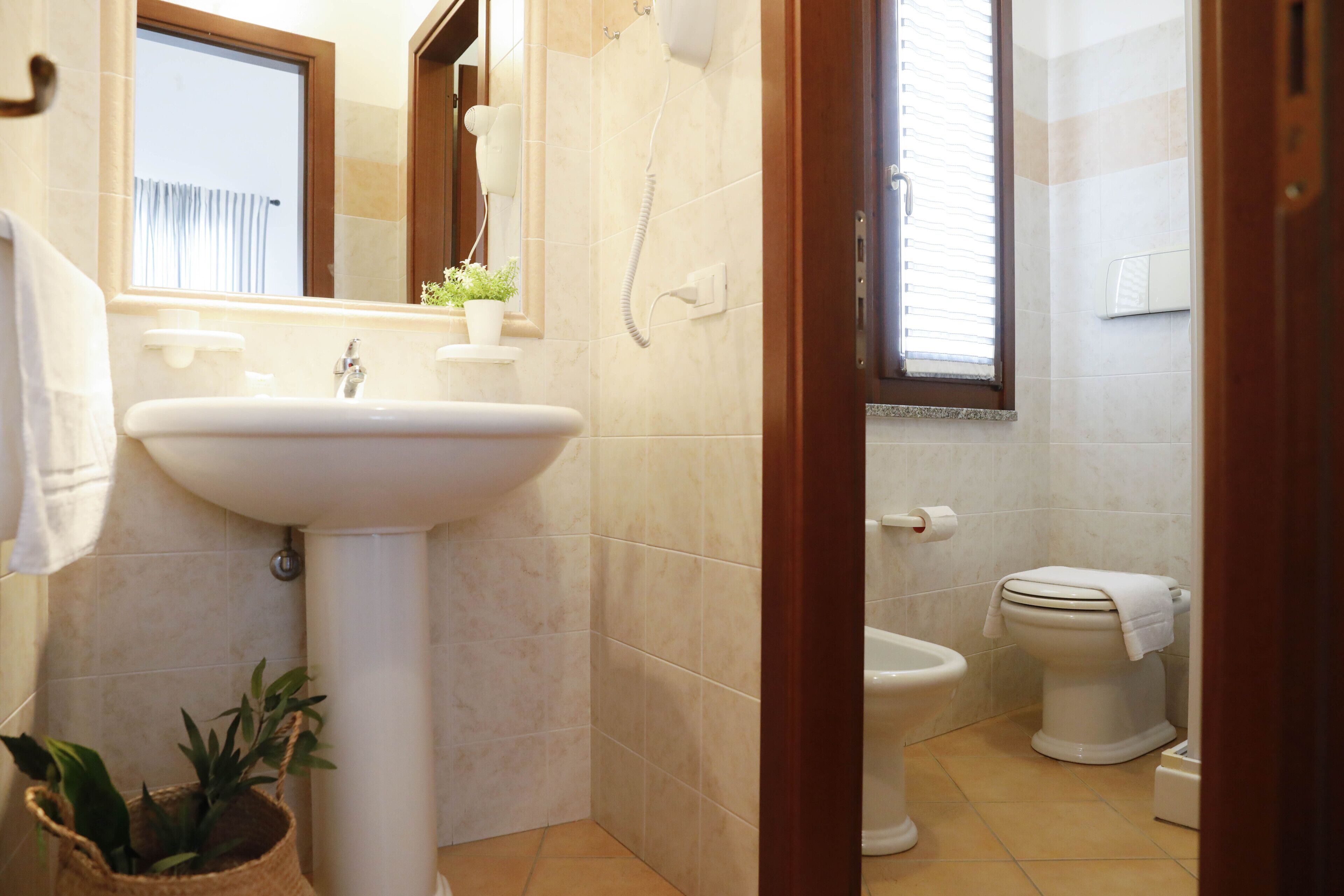 A bathroom with a sink, toilet, and a window.