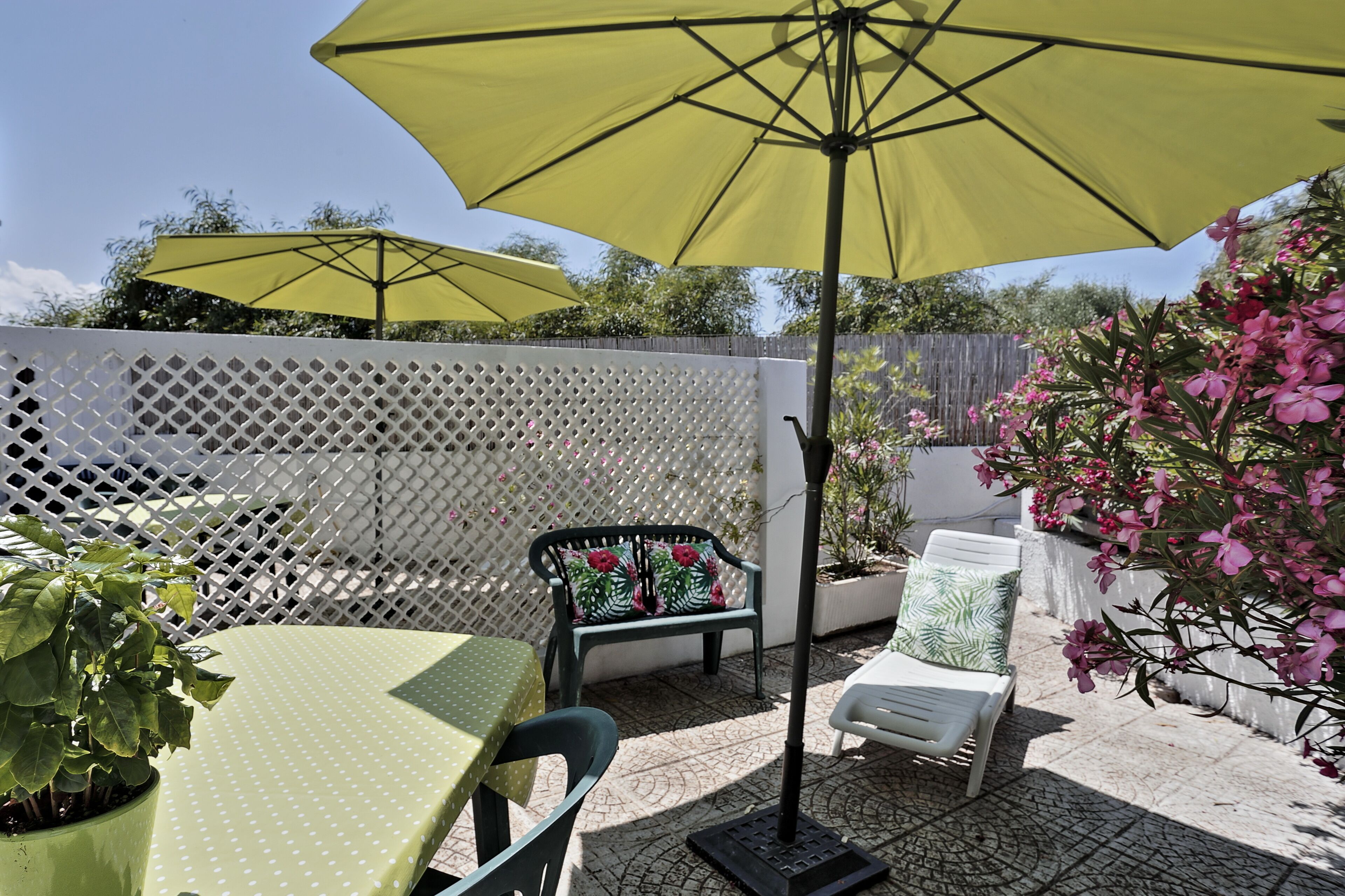 A patio with a table, chairs, and two yellow umbrellas.