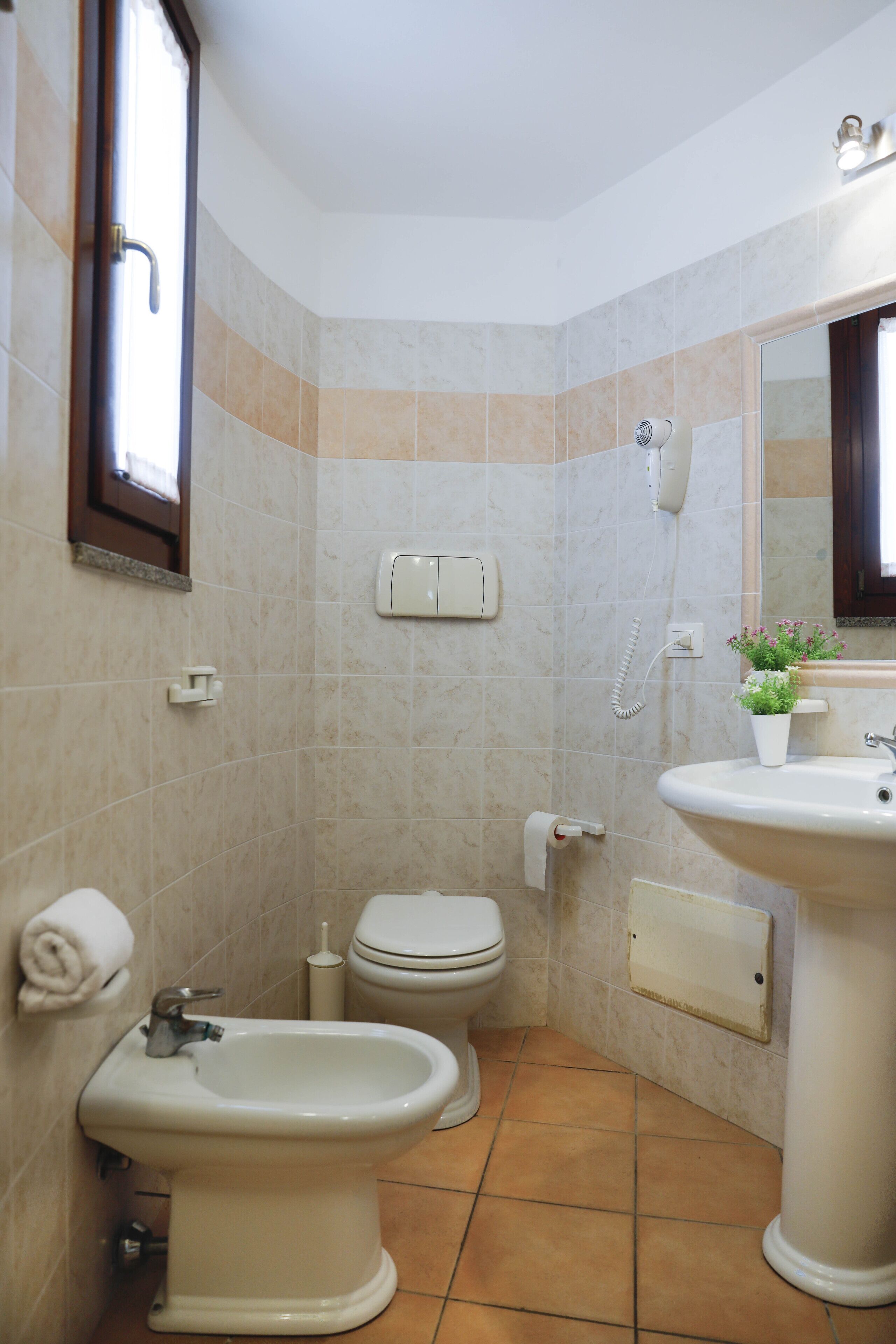 Une salle de bain équipée d’un bidet, de toilettes, d’un lavabo et d’un miroir.