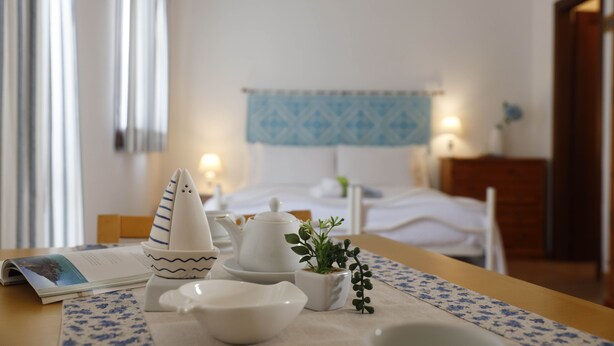 A neatly arranged table with a teapot, cups, and a small plant in a hotel room. - Il Melo Residence (Porto Torres)