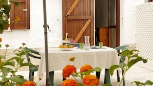 An outdoor patio with a table, chairs, and a table umbrella. - Il Melo Residence (Porto Torres)