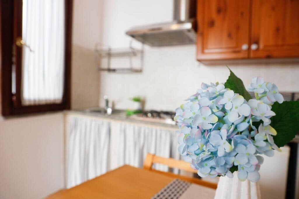 A dining table with a vase of flowers in the foreground.