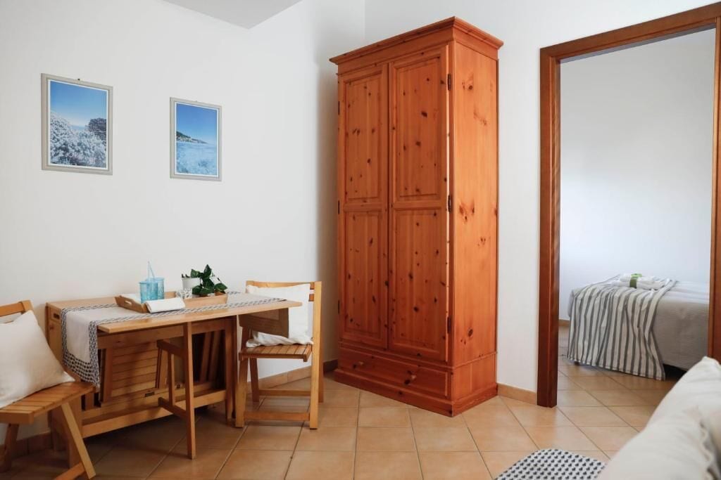 A room with a wooden table, chairs, a cabinet, and two framed pictures on the wall.