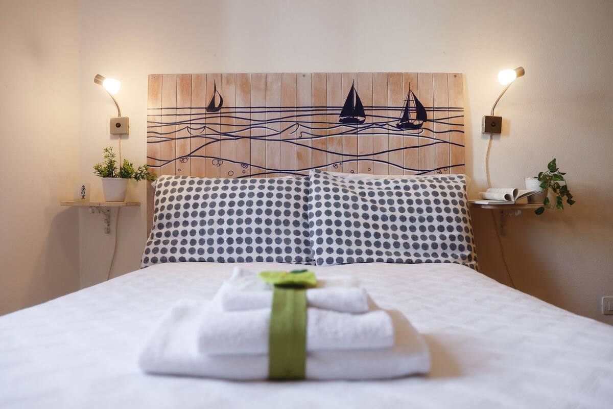 A neatly made bed with a polka dot pillow and a green towel on top.