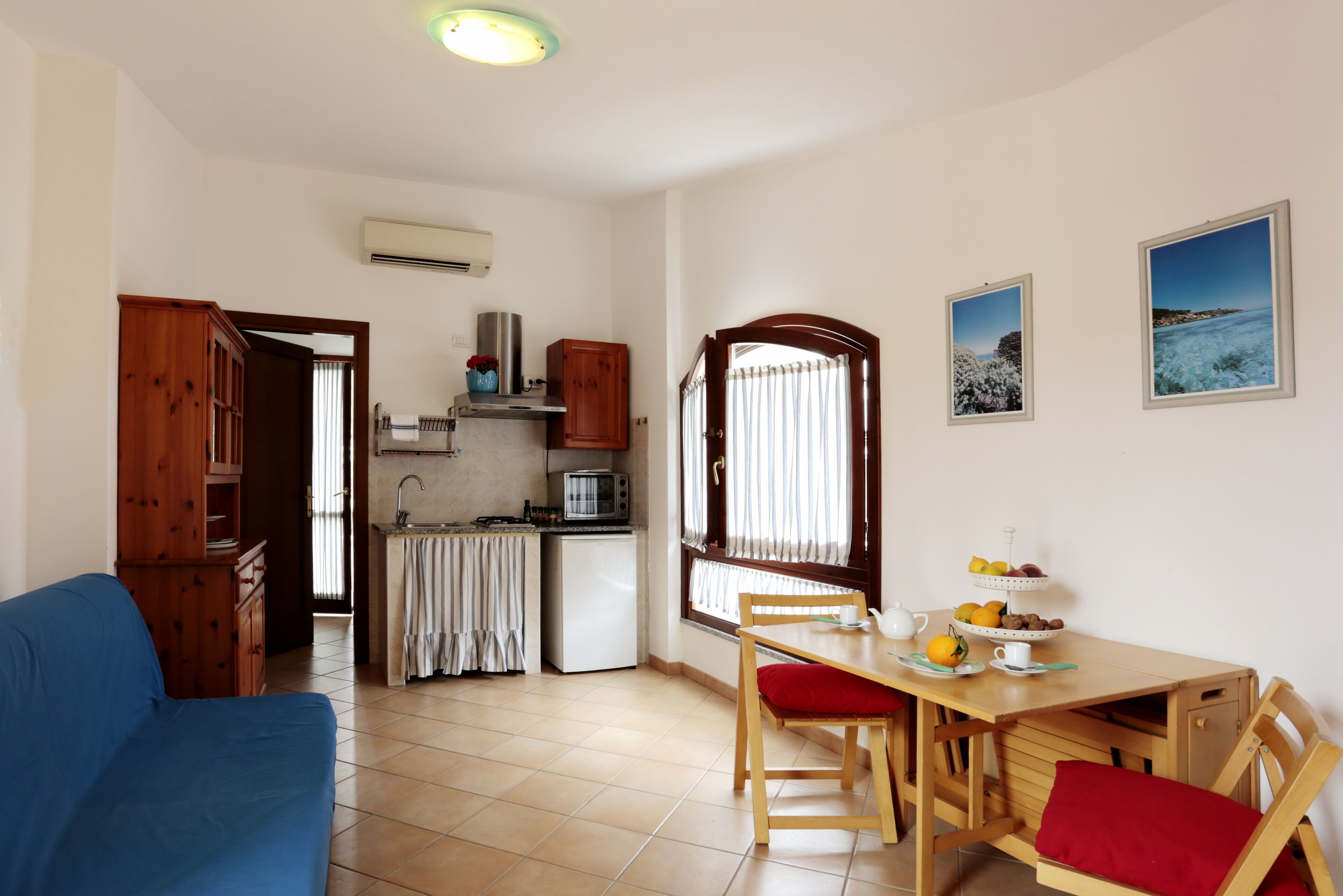 A compact living space with a kitchenette, dining area, and a blue sofa.