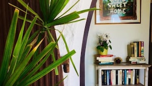 A room with a bookshelf, a framed picture, and a plant. - Il Melo Residence (Porto Torres)