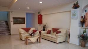 A spacious living room with a sofa set, a coffee table, and a staircase in the background. - Hotel Pyrgos (Chania)