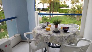 A balcony with a table set for breakfast, including a coffee cup, juice, and a bowl of fruit. - Exclusive studio Cala Blanca (Dénia)
