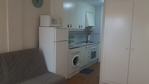 A compact kitchen with a washing machine, microwave, and oven. - Exclusive studio Cala Blanca (Dénia)