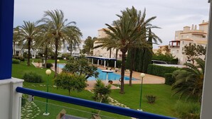 A pool area with palm trees, a blue railing, and a view of residential buildings. - Exclusive studio Cala Blanca (Dénia)