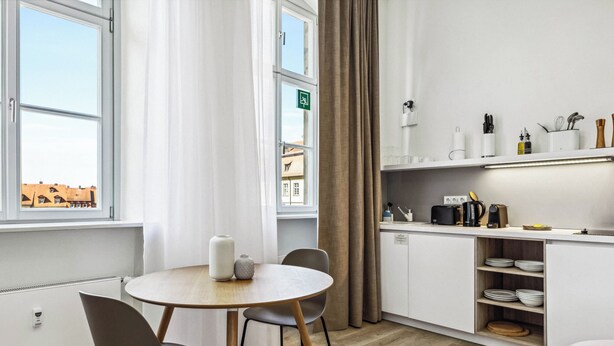 Een moderne keuken met een ronde houten tafel, twee stoelen en uitzicht op gebouwen.