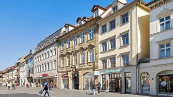 A historic European street with traditional architecture, including ornate facades and a cobblestone pavement.