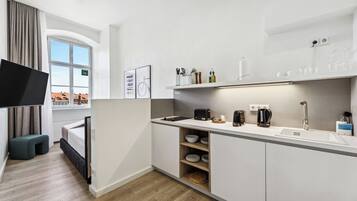 Una cucina moderna con mobili bianchi, un lavello integrato e un televisore a schermo piatto.