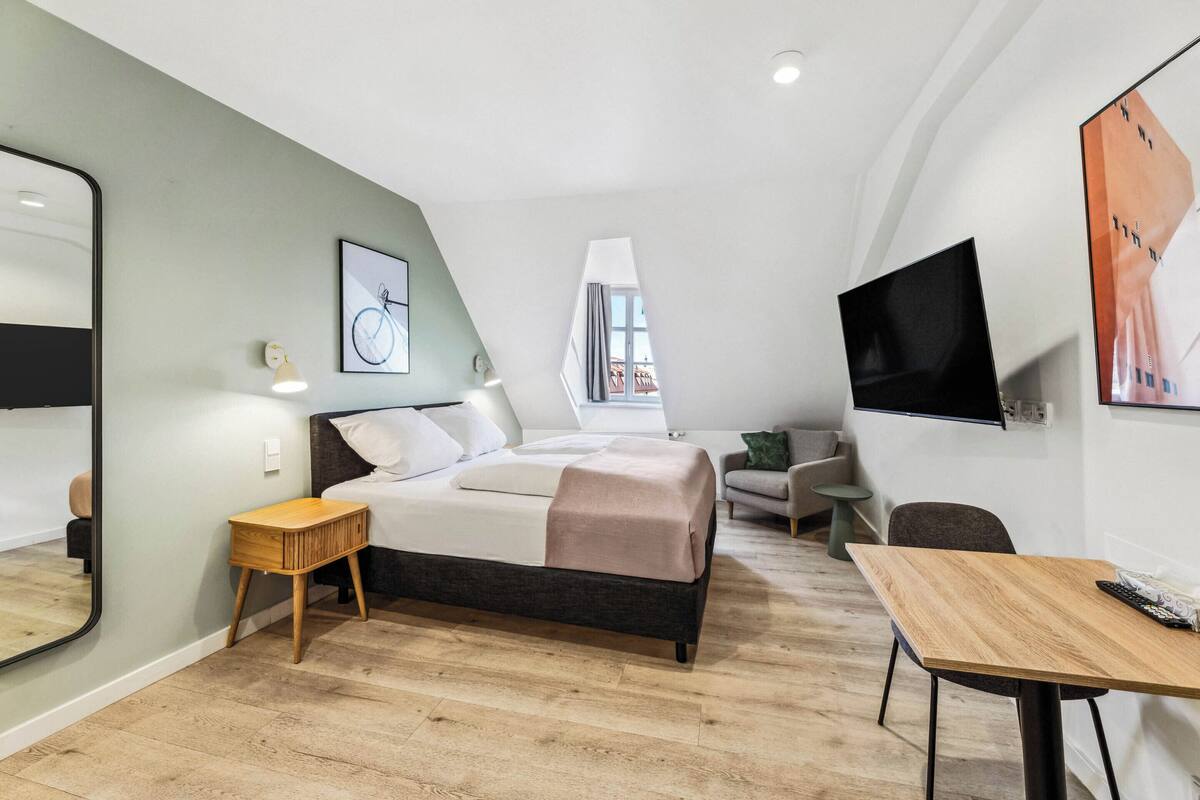 Ein modernes Schlafzimmer mit einem Bett, einem Nachttisch und einem an der Wand befestigten Fernseher.