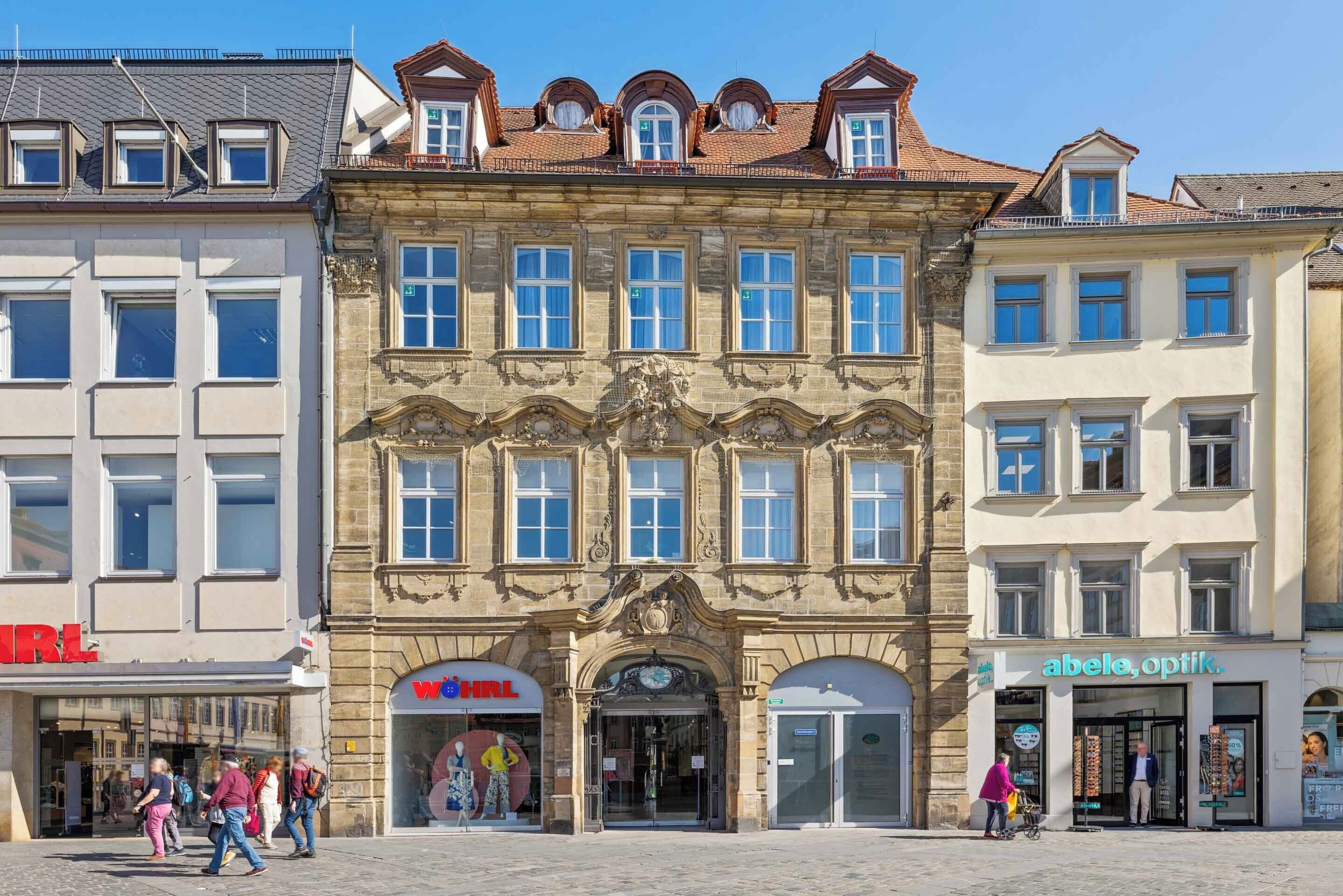 A historic building with multiple storefronts, including a visible 'HRL' sign and an 'abele, optik' sign.