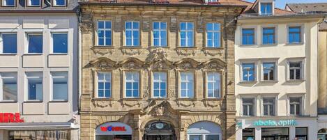 A historic building with multiple storefronts, including a visible 'HRL' sign and an 'abele, optik' sign.