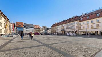 A cobblestone square with historic buildings, a clear sky, and people walking.