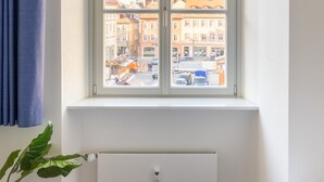 Een kamer met een groot raam, een radiator eronder en een gordijn aan de linkerkant.