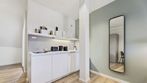 Een moderne keuken met witte kasten, een inbouw eiland en een grote spiegel aan de muur.