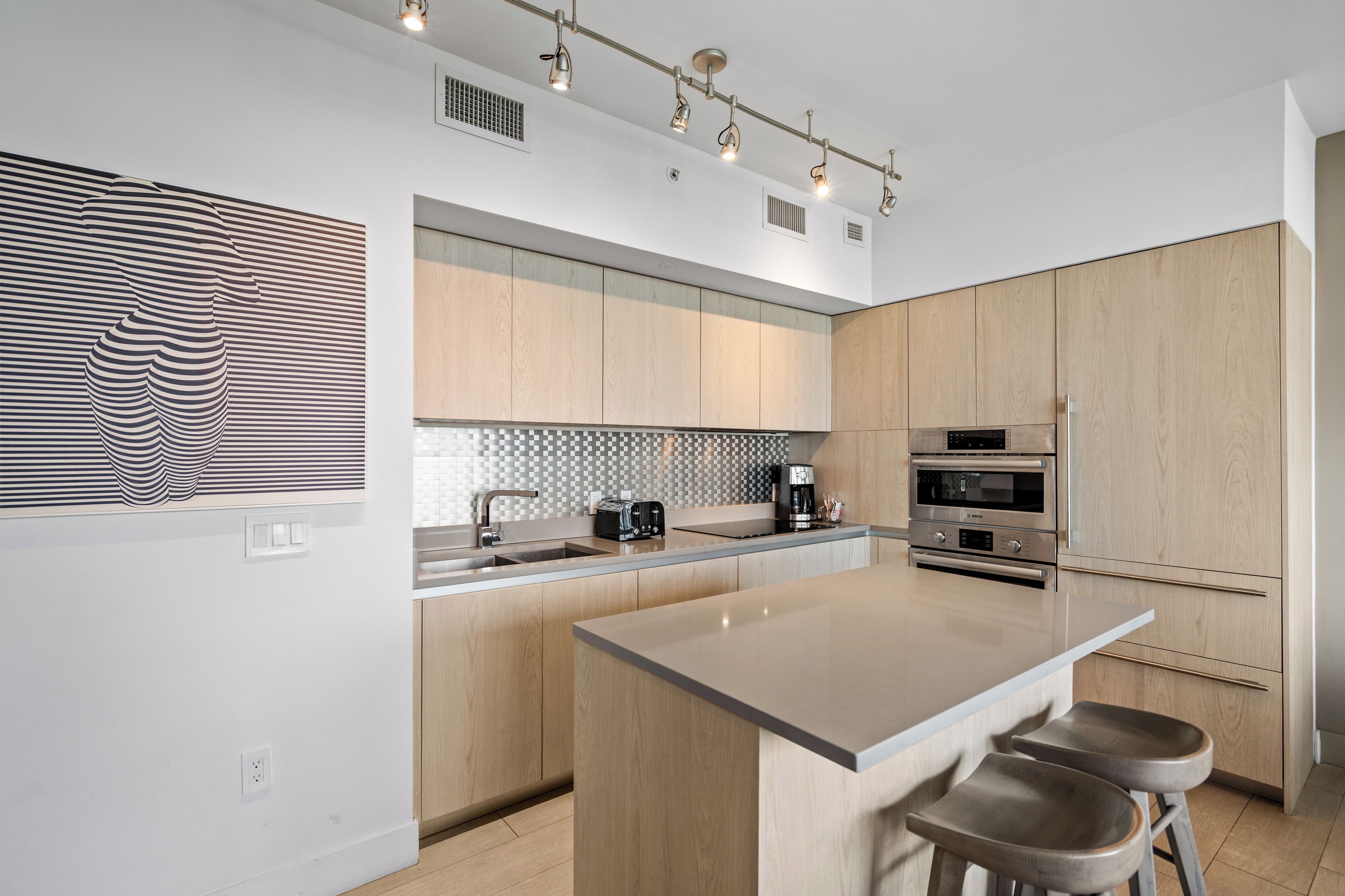 Una cocina moderna con una isla central, electrodomésticos integrados y decoración de pared a rayas.