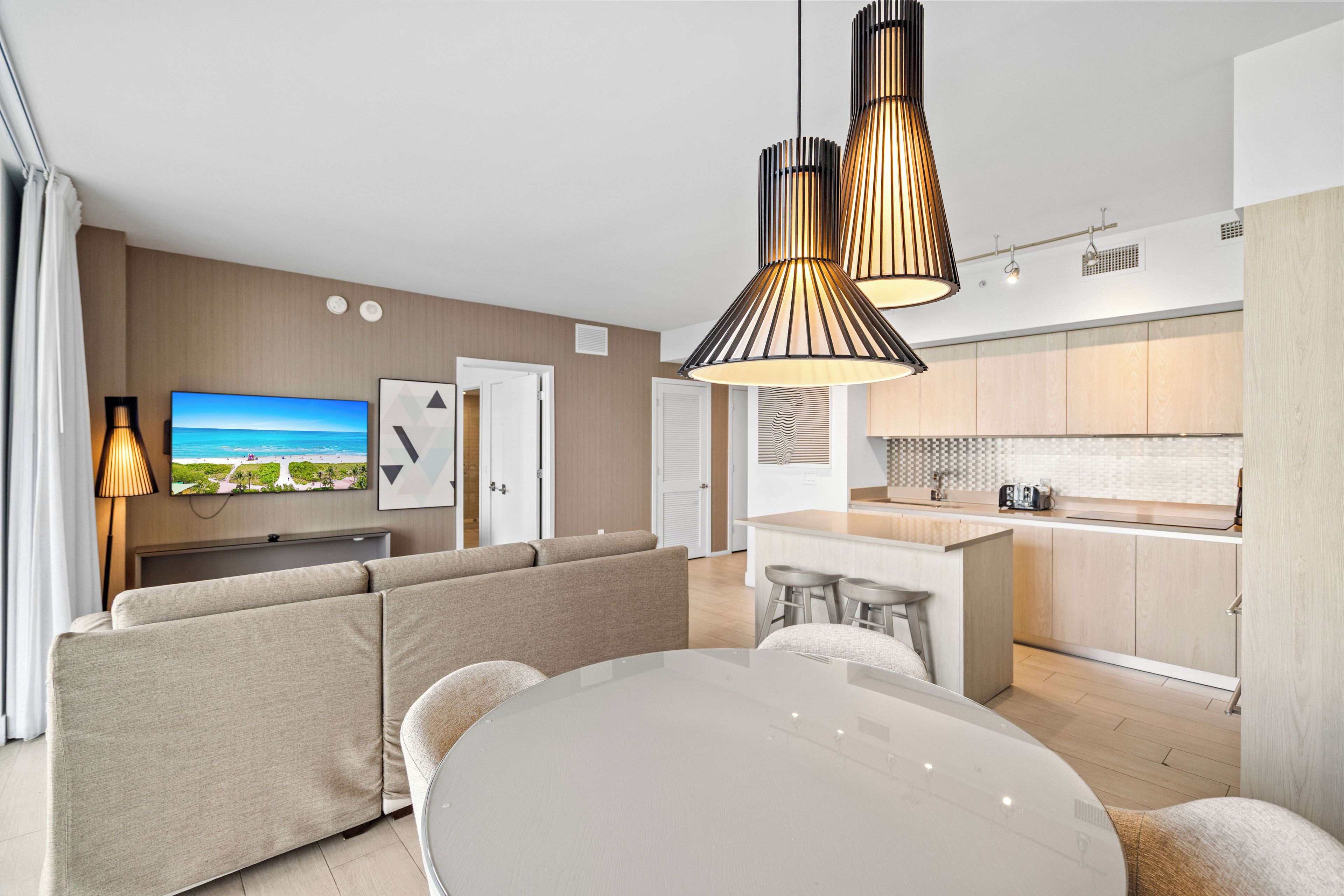 A modern living room with a sofa set, a dining table, and a kitchen area with a central island.