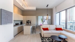 A modern apartment with a kitchen, living area, and large windows offering city views.