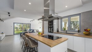 Een moderne keuken met een kookeiland, een inbouwoven en een roestvrijstalen afzuigkap.