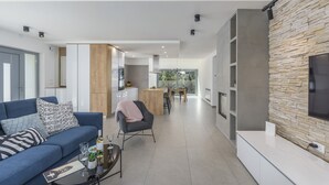 Een moderne woonkamer met een bank, salontafel en een televisie die aan een stenen muur is bevestigd.