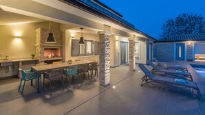 Een terras met buitenmeubilair, een steen-openhaard, een lounge bij het zwembad en een overdekte patio.