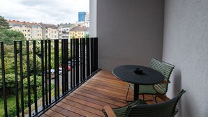 Un balcón con suelo de madera, una mesa redonda y dos sillas.