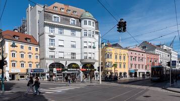 A street scene with tram tracks, buildings, and pedestrians.