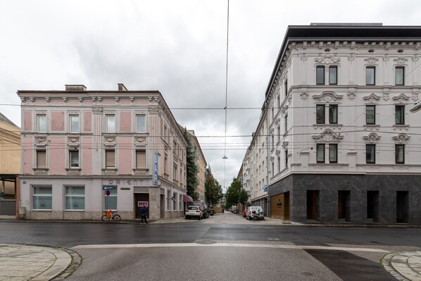 A street view with buildings on either side, a bicycle parked on the sidewalk, and a few cars parked along the street. - Limehome Linz Schillerstrasse (Linz)