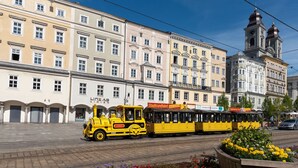 Un tranvía amarillo en una calle de la ciudad, con edificios históricos al fondo.