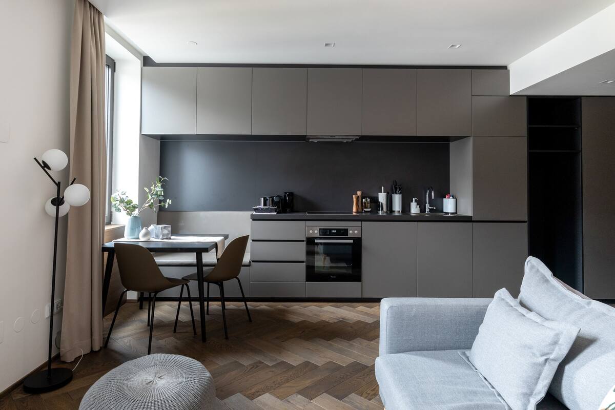 Eine moderne Küche mit Essbereich, ausgestattet mit Backofen, Kaffeemaschine und einem Esstisch mit Stühlen.