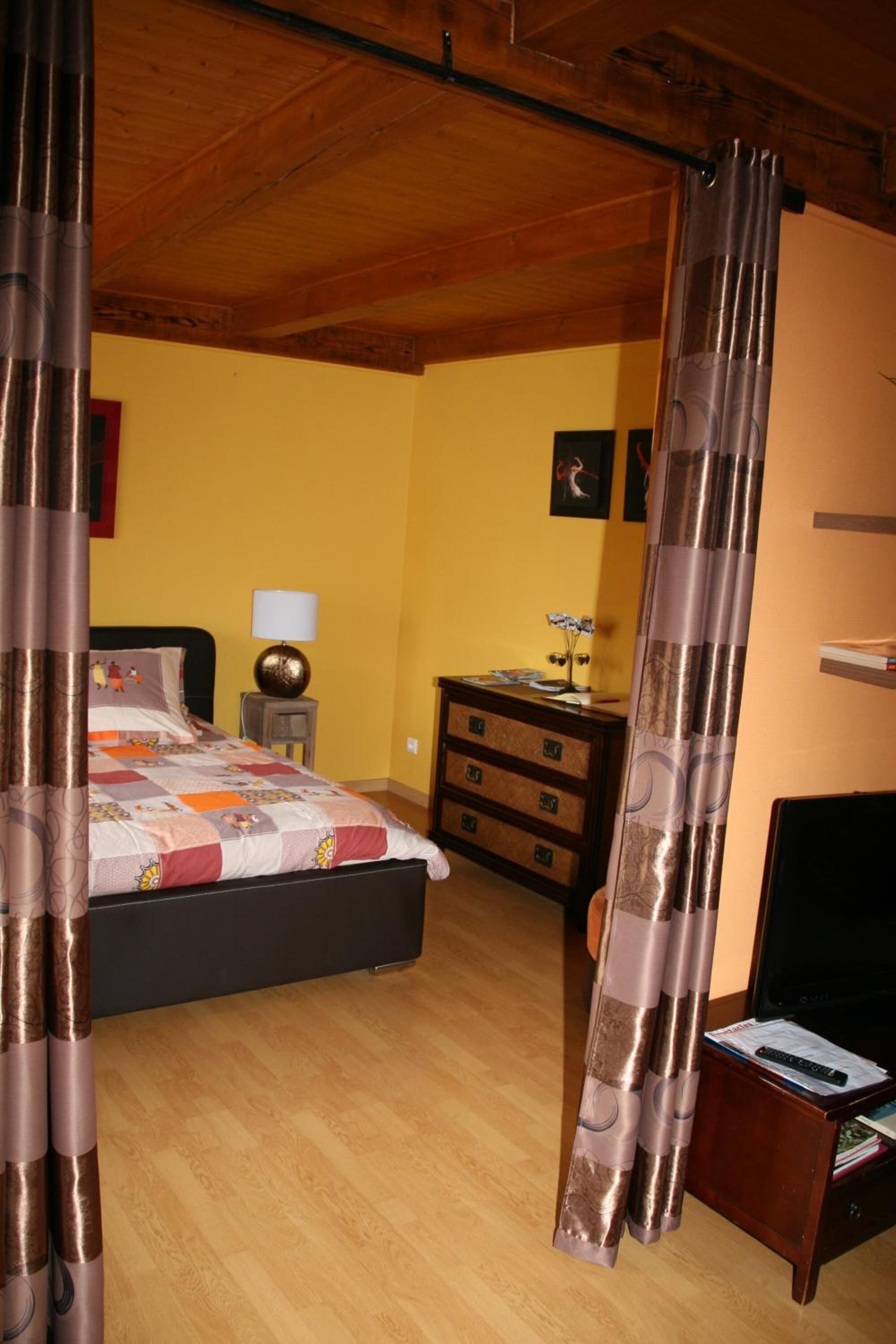 Un dormitorio con una cama, una mesita de noche, un tocador y un televisor.