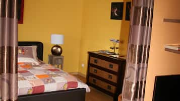 Un dormitorio con una cama, una mesita de noche, un tocador y un televisor.