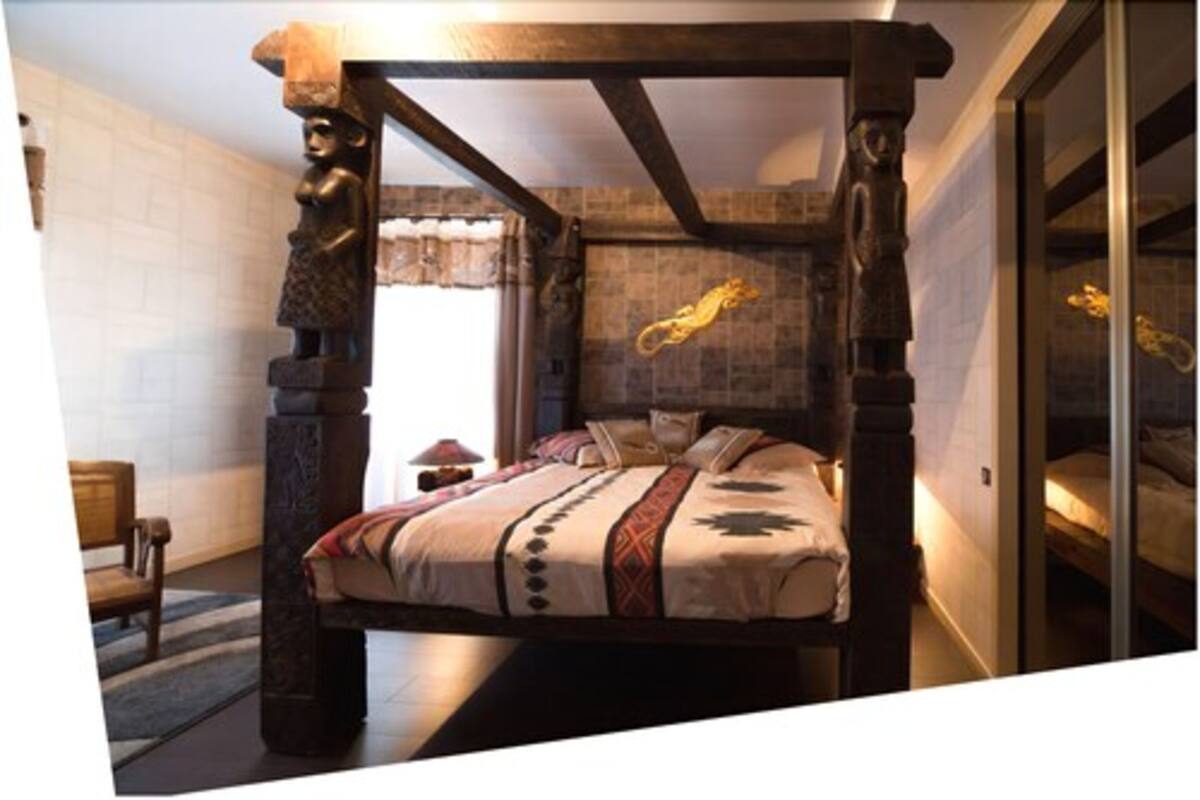 A bedroom with a four-poster bed, stone walls, and a large window.