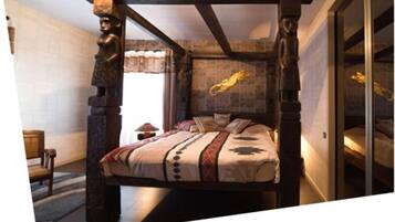 A bedroom with a four-poster bed, stone walls, and a large window.