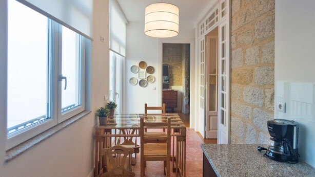 Une cuisine avec une table à manger, des chaises, une machine à café et un mur en pierre.