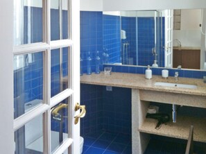 A bathroom with a blue tiled wall, a white sink, and a mirror. - One-Bedroom Apartment (Porto)