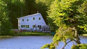 A house by a lake with a dock, surrounded by trees.