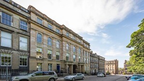 Ein historisches Gebäude mit mehreren Stockwerken, gro ßen Fenstern und einem markanten Eingang.