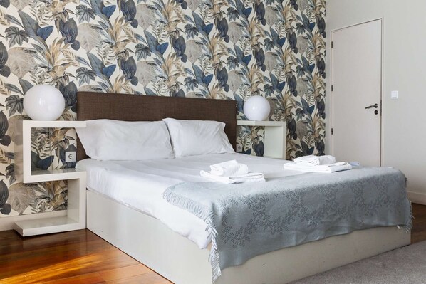 A neatly made bed with white linens and a grey blanket, flanked by white nightstands with spherical lamps. - Citybreak Apartments Lapa - Budget Duplex Studio (Porto)