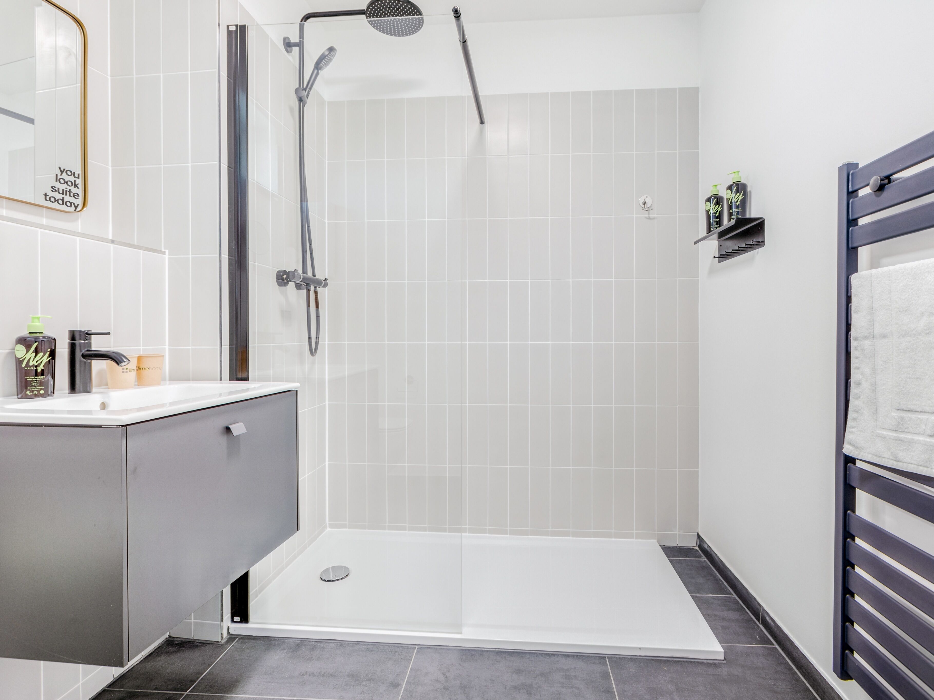 A modern bathroom with a shower, a vanity, and a towel rack.