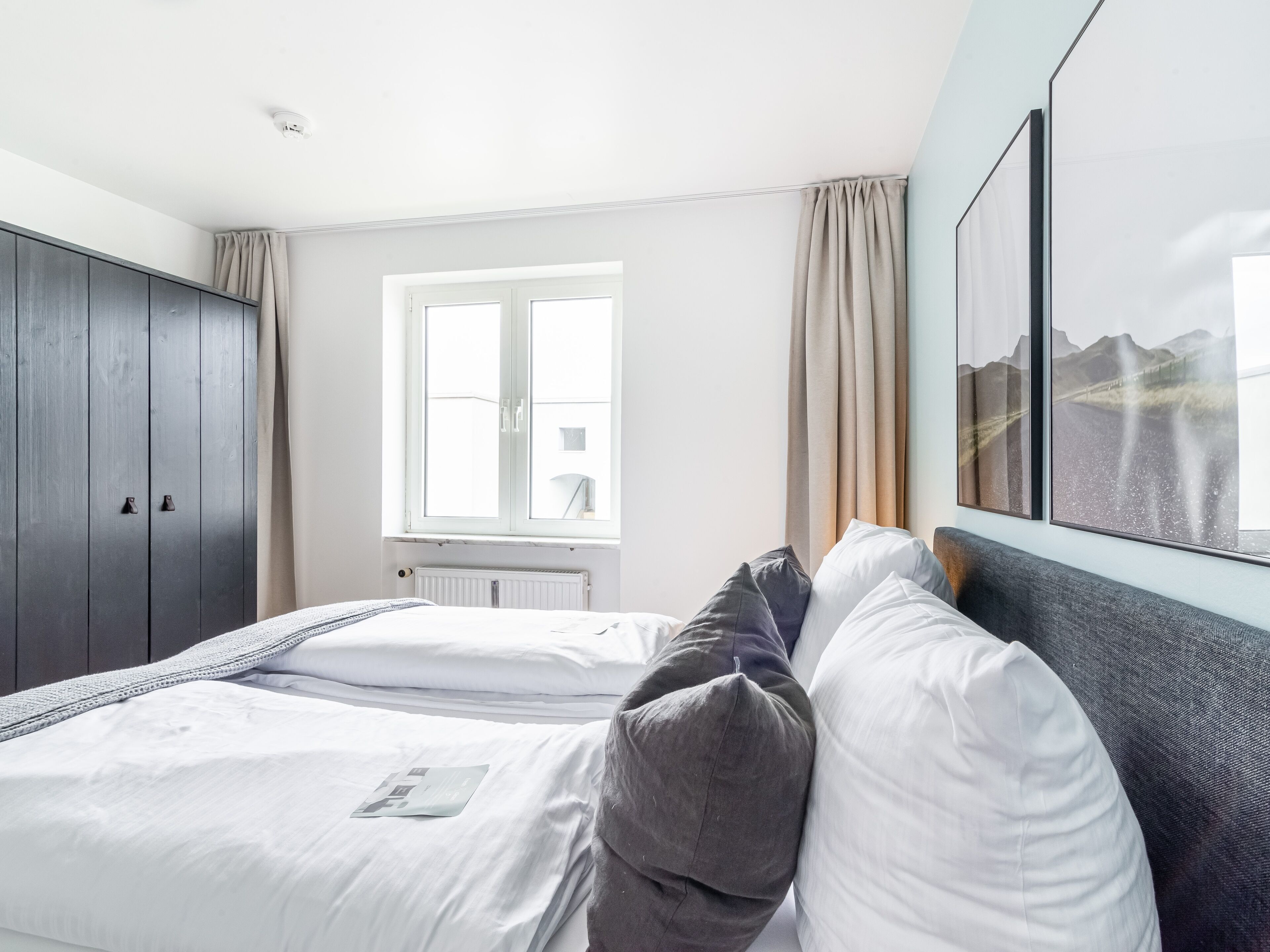 Ein Hotelzimmer mit einem Bett, einem Schrank, einem Fenster und einem Bild an der Wand.