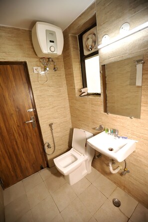 A bathroom with a toilet, bidet, sink, and a mirror. - ADB Rooms Hotel Noratan Palace (New Delhi)