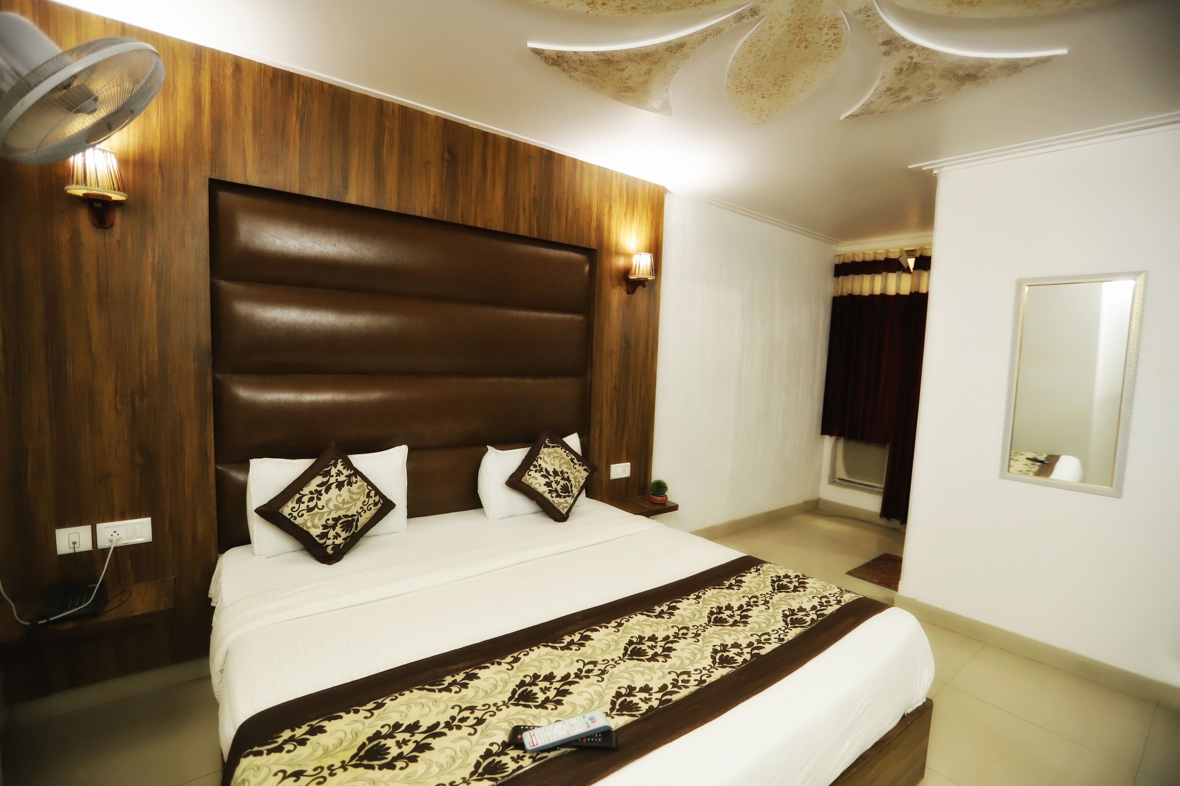 Ein Hotelzimmer mit einem großen Bett, einem Holzkopfstück und einer Nachttischlampe.