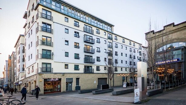 A multi-story building with a ground-level commercial space on the left and a restaurant on the right. - Contemporary Holyrood Apartment (Edinburgh)